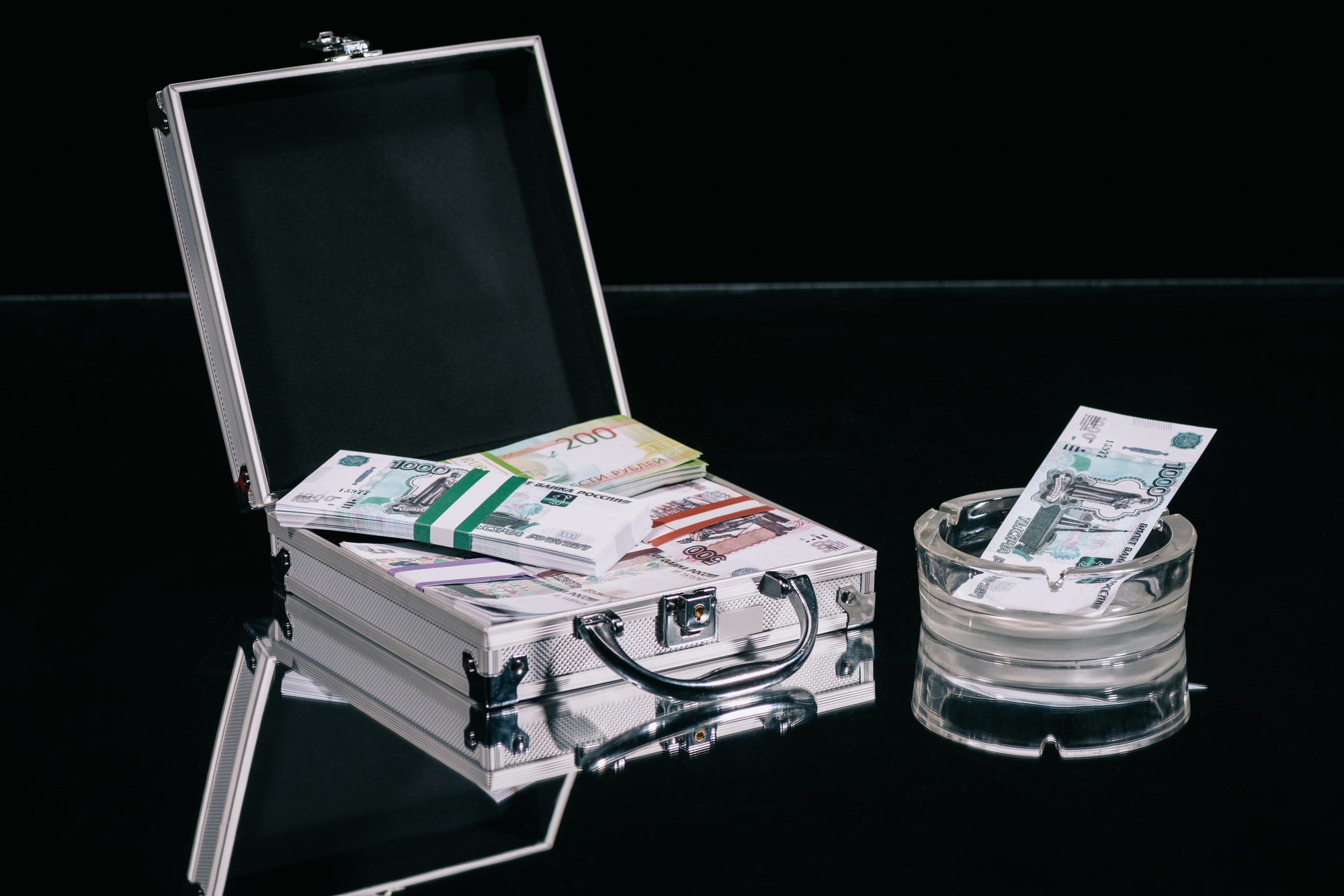 russian rubles banknotes in suitcase safe box and money in ashtray on black